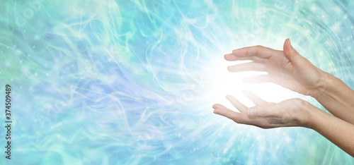 Faith Healers website banner background - female hands with bright white healing energy between against a wide blue green energy formation background with copy space 
