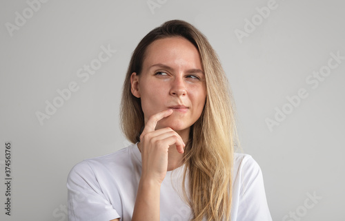 Puzzled perplexed young woman with distrustful face isolated on grey studio wall, unbelieving suspicious girl looking aside doubtful uncertain