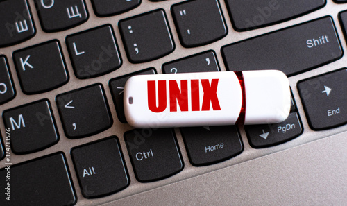 UNIX - the word on a white flash drive, lying on a black laptop keyboard