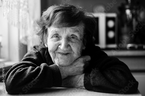 Black and white close-up portrait of old woman in her home.
