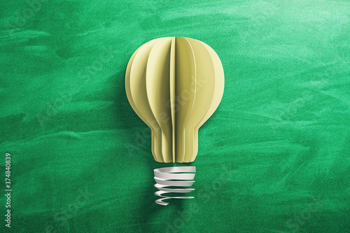 Yellow light bulb made from paper on blackboard background.