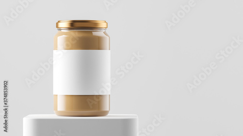 Big tall transparent glass jar with copper metal cap and blank label filled by nut butter on the podium over white background.