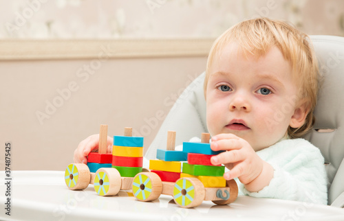 An inquisitive kid plays with educational toys while sitting at his children's table. Close up. Copy space
