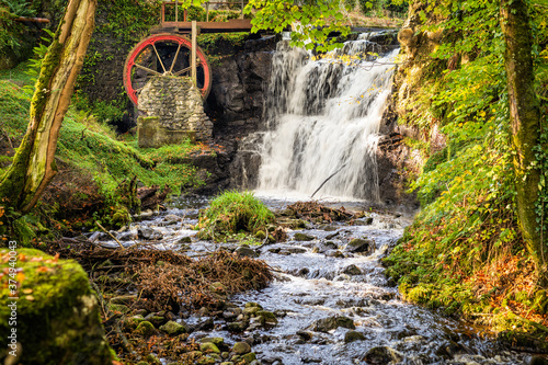 Vintage red waterwheel with waterfall in autumn colours in Glenariff Forest Park, Count Antrim, Northern Ireland