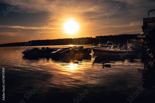 Jachty i łodzie zacumowane w porcie na tle zachodzącego słońca.