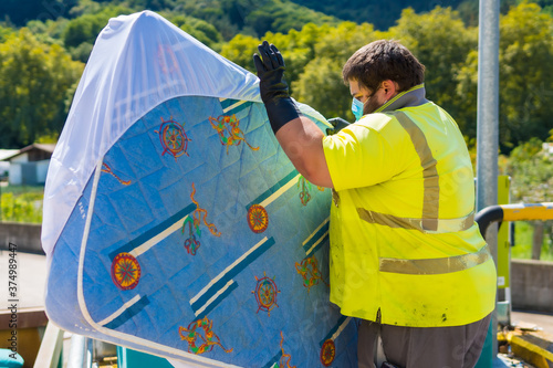 Worker in a recycling factory or clean point and garbage with a face mask and with security protections, new normal, coronavirus pandemic, covid-19. Operator cleaning and ordering the installation