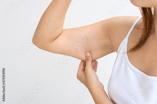 Young Asian woman pinching loose skin or flab on her upper arm