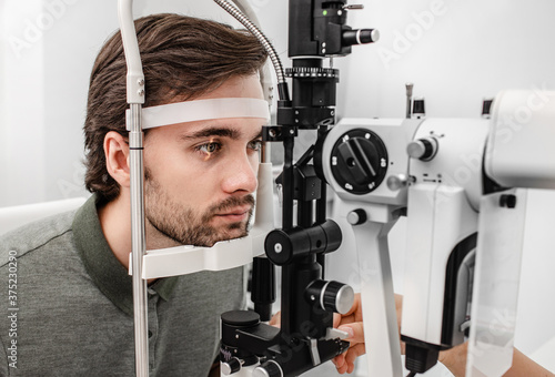 Adult man getting an eye exam at ophthalmology clinic. Checking retina of a male eye close-up