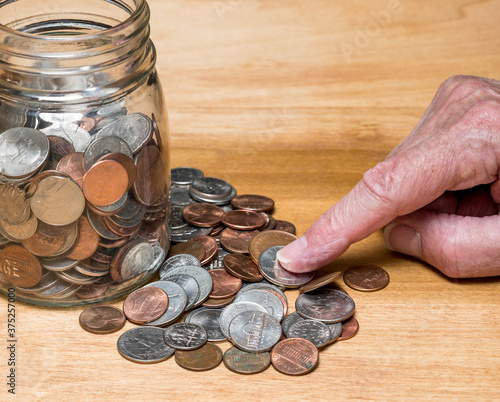 Hundreds of US coins in a savings jar on wooden table as concept for hoarding during shortage of loose change in USA