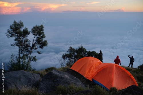 A climber enjoying the sunrise not far from his tent on Mount Sumbing