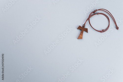 Closeup of a wooden tau cross necklace isolated on a gray background