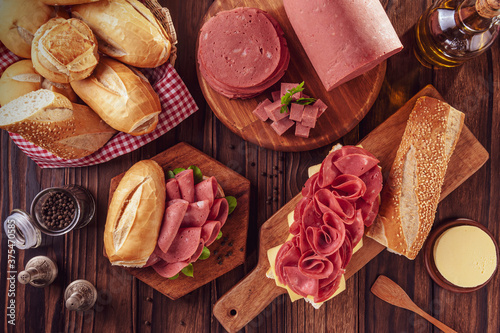 Mortadella sandwich on a wood cutting board with bread, butter and spices - Top view