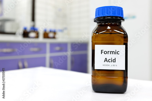 Selective focus of Formic acid solution in brown amber bottle. Blur white laboratory backdrop with copy space.