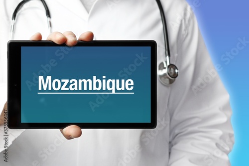 Mozambique. Doctor holds a tablet computer in his hand. Close up. Text is on the display. Blue Background