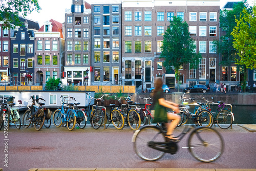 Young blurred woman in green dress with bag riding a bicycle in Amsterdam city, Netherland
