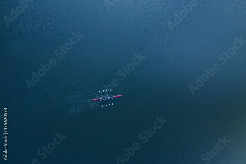 Boat coxed four rowers rowing on the blue river aerial drone top view