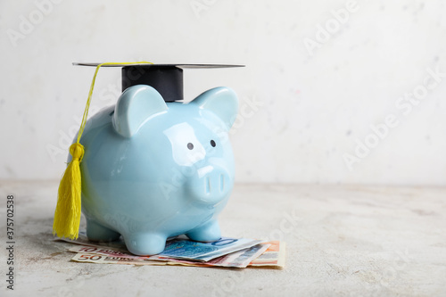 Piggy bank with graduation hat and money on table. Tuition fees concept