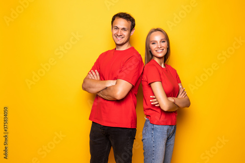 Portrait of cool couple in red shirts looking at camera isolated on yellow background.