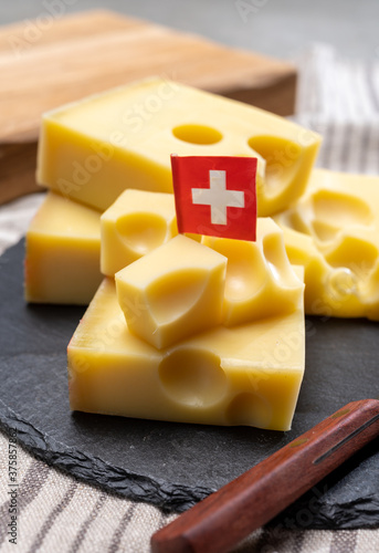 Block of Swiss medium-hard yellow cheese emmental or emmentaler with round holes and cheese knife