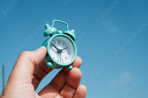 man with an alarm clock in his hand outdoors