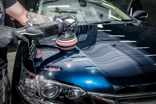 Man with orbital polisher polishing car.