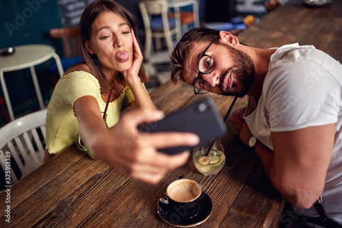 Young couple taking silly selfie in a cafe