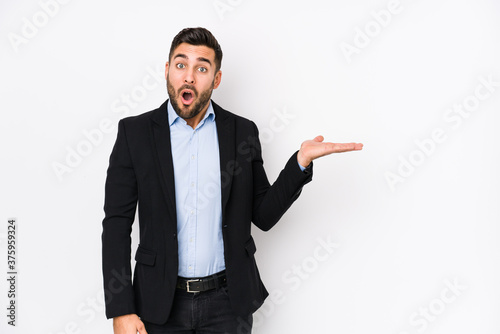 Young caucasian business man against a white background isolated impressed holding copy space on palm.