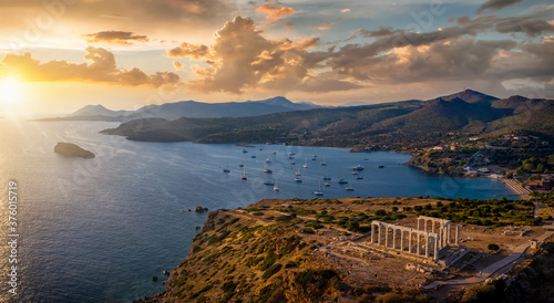 Panorama des Kap Sounion bei Athen zum Sonnenuntergang mit Tempel des Poseidon und zahlreichen Segelbooten vor Anker in der Bucht, Attika, Griechenland