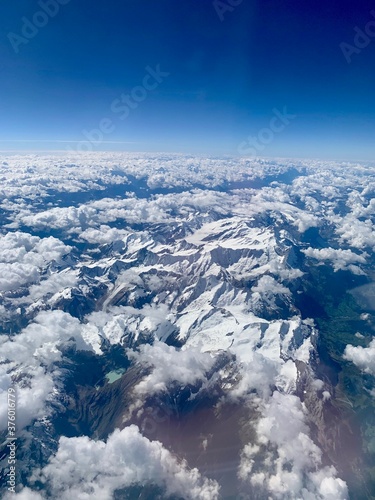 View of the Italian alps from an airplane. The Alps have snow even though it's early September. No people. 