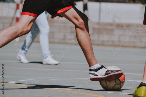 Las piernas de un chico delgado corriendo detrás del balón de fútbol