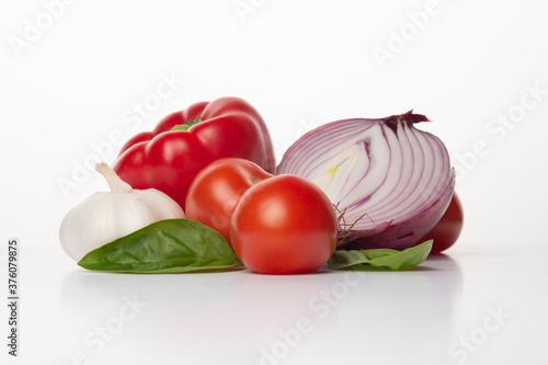 Fresh vegetables on a white background. Ingredients for Gazpacho or tomato sauce: red onion, basil, red pepper, garlic ant tomatoes. 