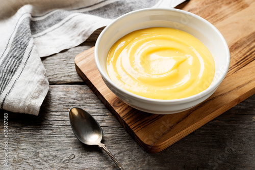 Homemade vanilla custard pudding or lemon curd in a white bowl.