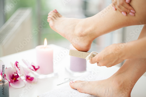 Woman cleans the heel of the foot with pumice