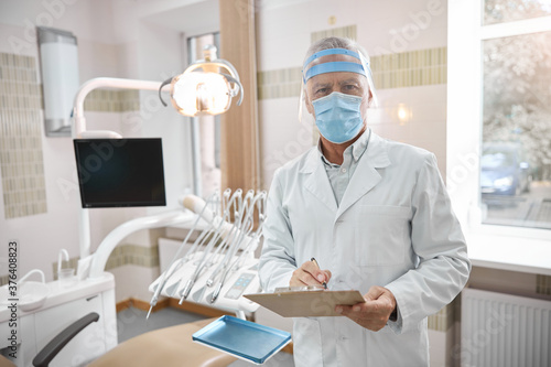 Qualified dentist looking at the screen of a tablet