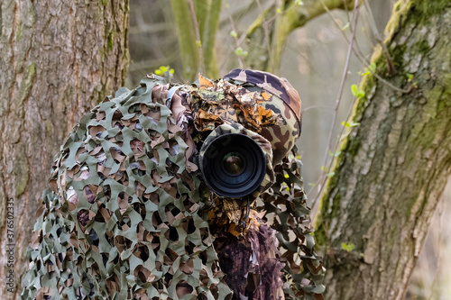 Zamaskowany fotograf przyrody czeka na zwierzynę, maskowanie, fotografia przyrodnicza, siatka maskująca