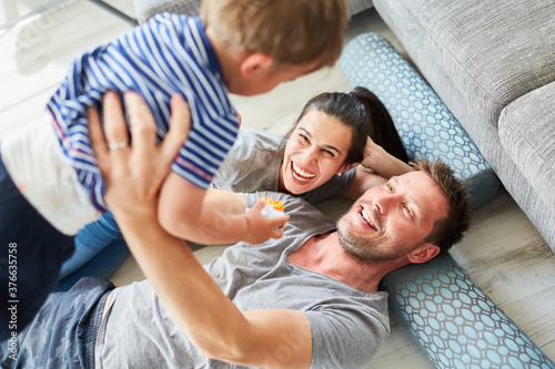 Glückliche Eltern heben Sohn hoch als Familie zu Hause