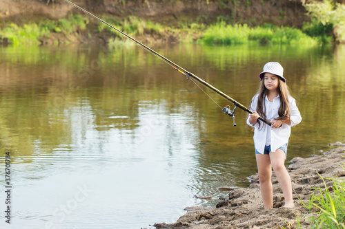 happy little girl with fishing rod on summer river