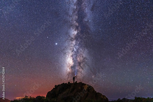 A young man with a flashlight below the beautiful milky way of the Caldera de Taburiente near the Roque de los Muchahos on the island of La Palma, Canary Islands. Spain, astrophotography