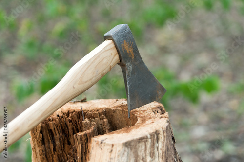 Large splitting axe with sharp metal head and wooden handle in stump on natural landscape outdoors, tool