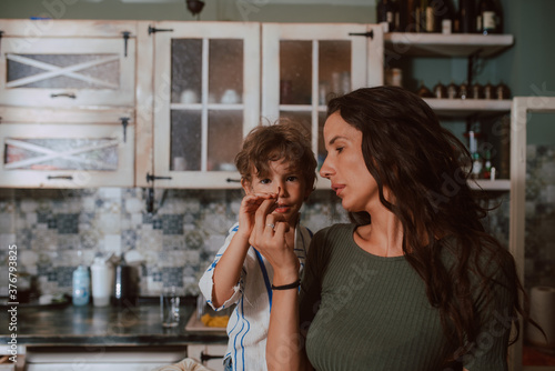 A beautiful caucasian mother feeds her son in the kitchen. Time with family