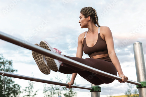 Woman athlete during calisthenics workout on a parallel bars
