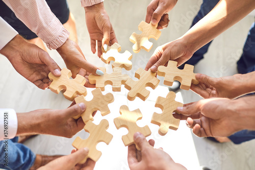 Company employees playing game and joining pieces of jigsaw puzzle during team building activity