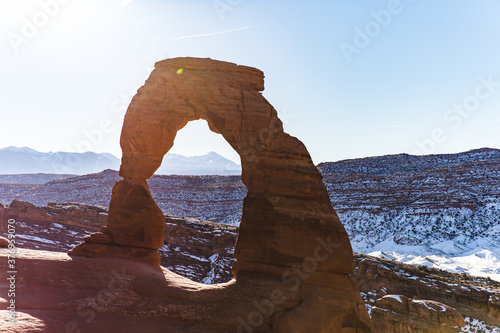 close up of an arch rock formation made by erosion in a desert with snow on the ground