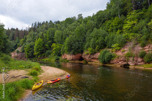 landscape with sandstone cliffs, canoes and kayaks on the river bank, fast flowing and clear river water, Kuku cliffs, Gauja river, Latvia