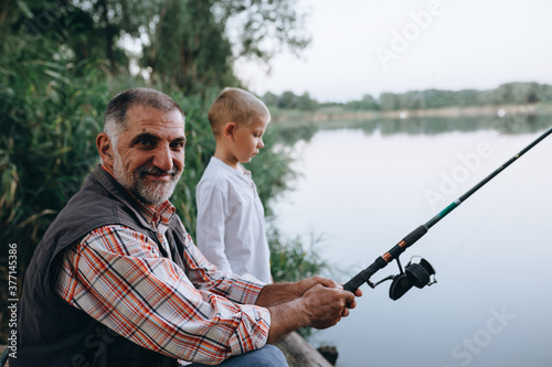 grandfather with his grandson fishing outdoor on the lake