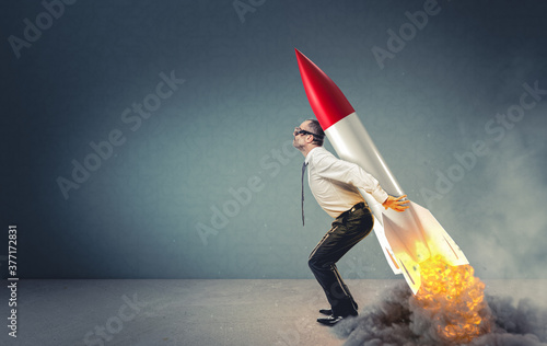 businessman with rocket on his back ready to take off.