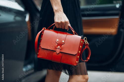 Women is holding handbag near the luxury car