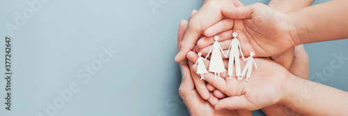 Adult and children hands holding paper family cutout, family home, foster care, homeless charity support concept, family mental health, budgeting during recession concept