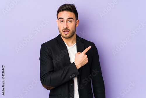 Young caucasian man isolated on purple background pointing to the side