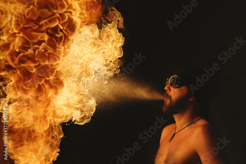 Male fakir blowing out fire in an abandoned building at night. Fire performer blowing out fire close-up.